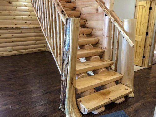 Milled half log tread staircase with flare butt tree newels.