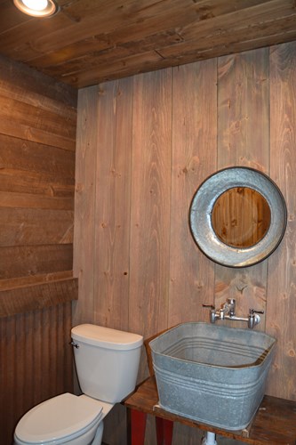 Powder room with circle sawn barn wood in weathered red with cowboy steel wainscoting.