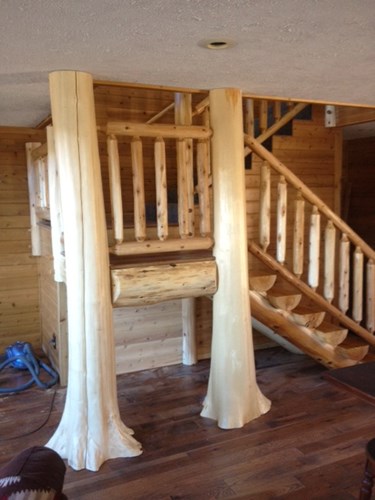 Two flared tree trunks used as posts on a log staircase. rustic railing