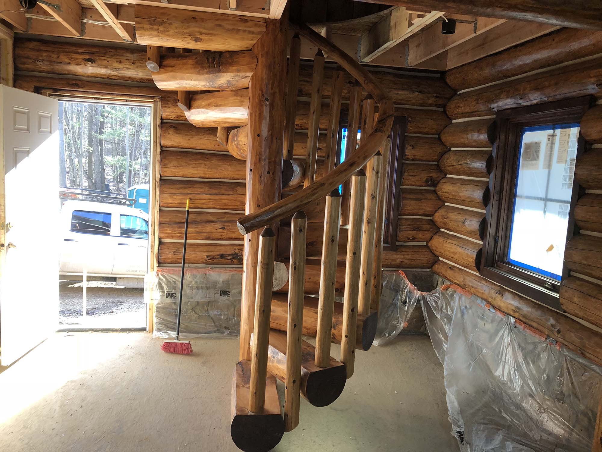 Custom half log spiral staircase with white cedar log railing.
