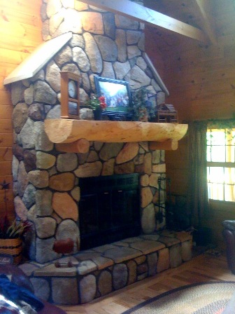 Milled timber log mantel around a stone fireplace.